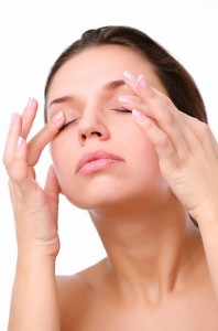 Young woman pushes with fingers on closed eyes. Isolated over white.